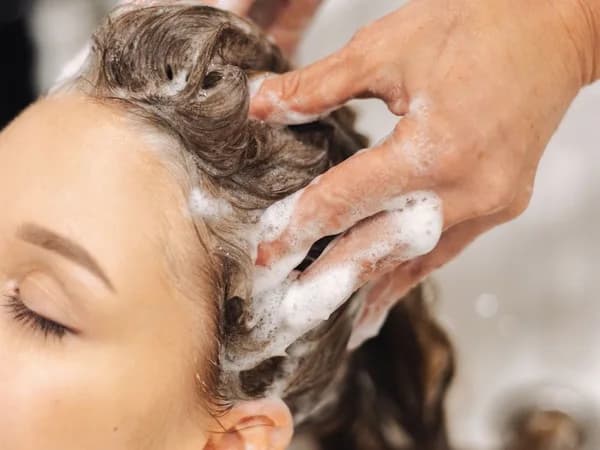 Stylist washing a client's hair at a salon basin